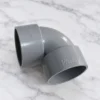 Elbow PVC 1 1/2 Inch Pralon DV berwarna abu-abu dengan markasi ukuran pada badan fitting