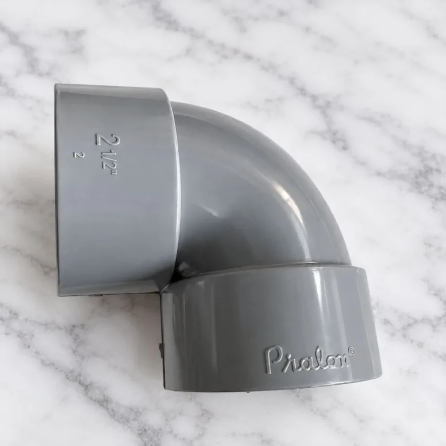Elbow PVC 2 1/2 Inch Pralon DV dengan soket double valve, logo Pralon tercetak di bodi fitting berwarna abu-abu