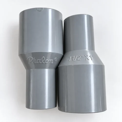 Dua Socket PVC Pralon 1 1/2 x 1 Inch TS berwarna abu, satu bertuliskan Pralon dan satu bertuliskan ukuran 1 1/2" X 1"