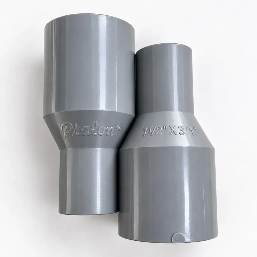 Dua fitting socket PVC Pralon berwarna abu berdampingan, satu bertuliskan Pralon dan satu bertuliskan 1 1/2" X 3/4", Socket 1 1/2 x 3/4 Inch TS Merek Pralon